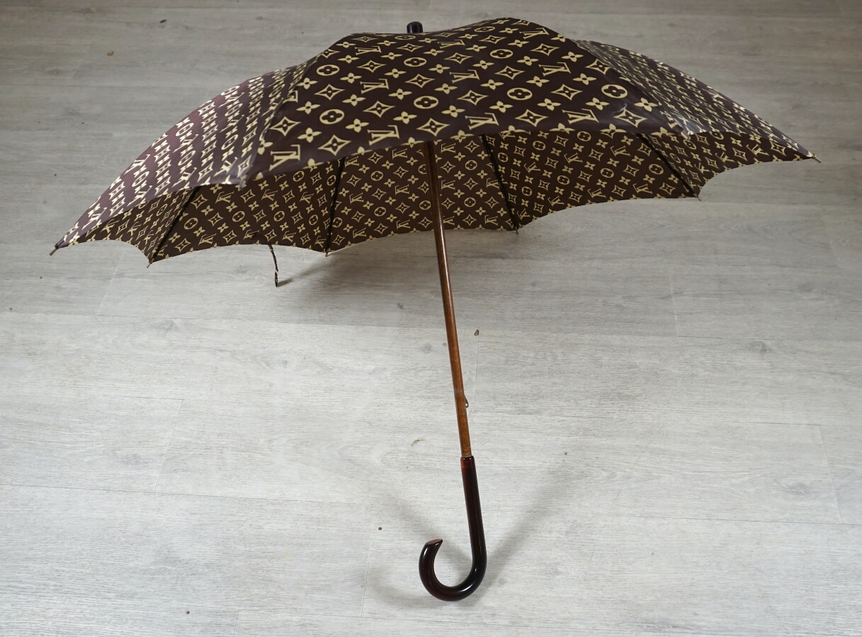 Louis VUITTON : Parapluie en toile Monogram, poignée en résine ambrée, L.  75 cm.